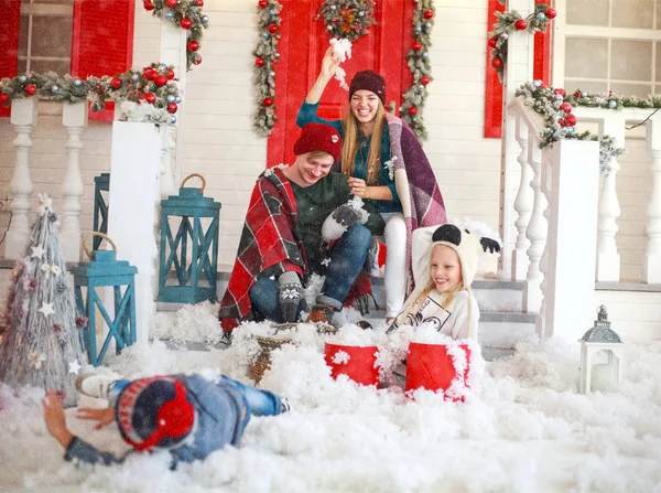 Радостная семья с детьми, играющими в снежки во дворе — стоковое фото