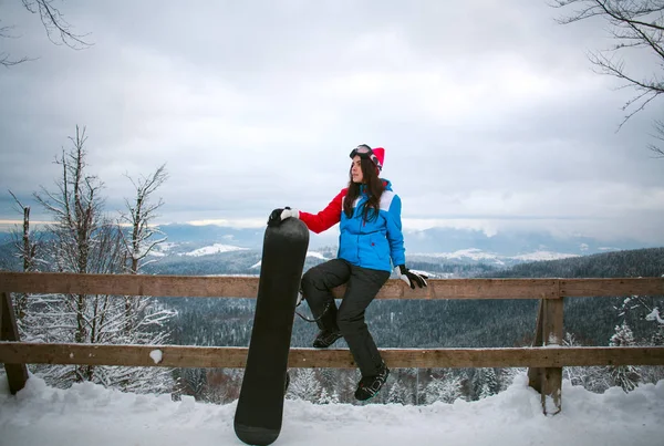 Jovem com snowboard alto em montanhas na temporada de inverno — Fotografia de Stock