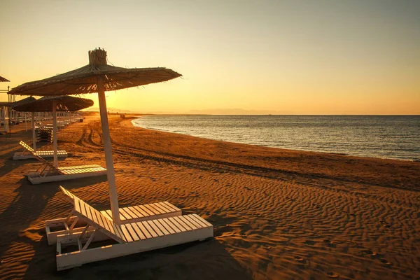 Camas de sol na praia de areia vazia junto ao mar ao pôr-do-sol, Montenegro — Fotografia de Stock