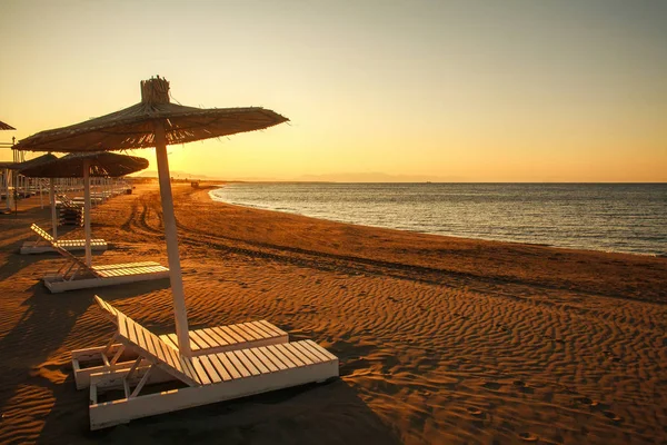 Sunbeds on empty sand beach by the sea at sunset, Montenegro — Stock Photo, Image