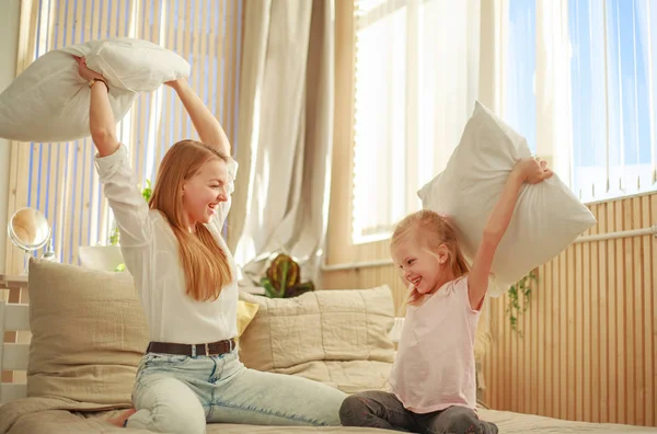 Moeder en dochter spelen vrolijk samen met kussens thuis — Stockfoto