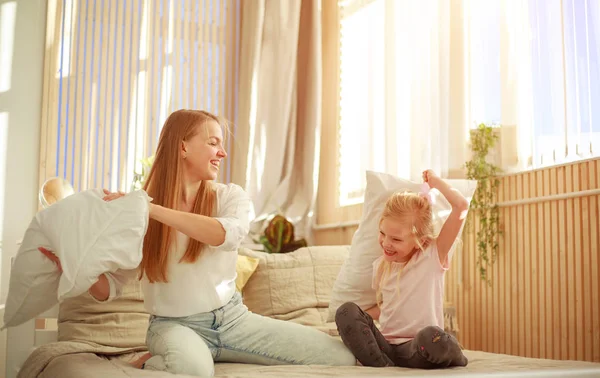 Moeder en dochter spelen vrolijk samen met kussens thuis — Stockfoto