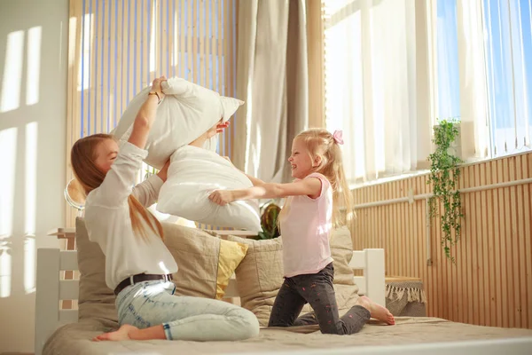 Mother and daughter joyfully play together with pillows at home — Stock Photo, Image