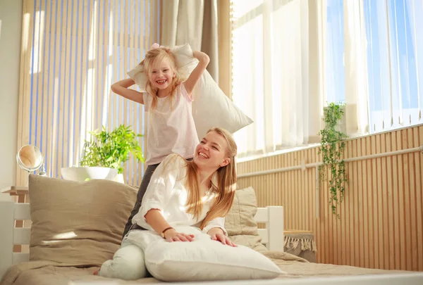 Moeder en dochter spelen vrolijk samen met kussens thuis — Stockfoto