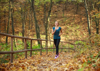 Genç zayıf kadın orman parkında koşuyor, sağlıklı bir yaşam tarzı var.