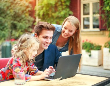 Genç bir aile, kızlarıyla birlikte dizüstü bilgisayara bakıyor. 