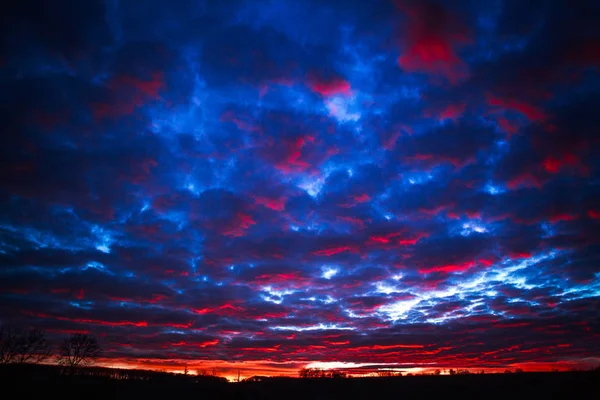 Wunderschöner farbenfroher Sonnenuntergang am wolkenverhangenen blauen Himmel in Feld und Wald — Stockfoto