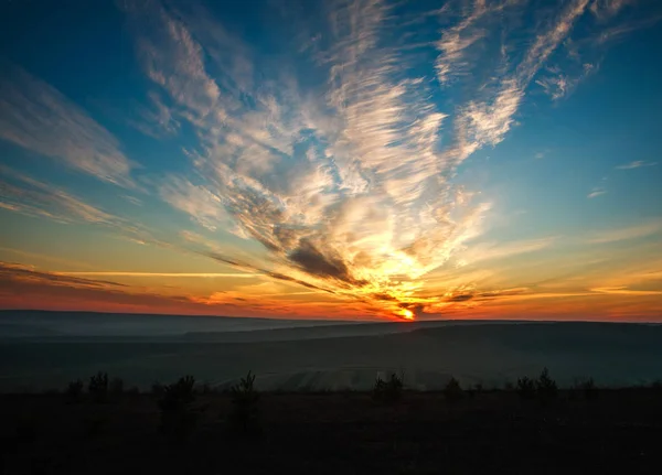 Gorgeous colorful sunset on cloudy blue sky in field and forests — Stock Photo, Image