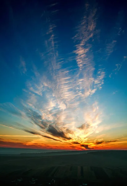 Wunderschöner farbenfroher Sonnenuntergang am wolkenverhangenen blauen Himmel in Feld und Wald — Stockfoto