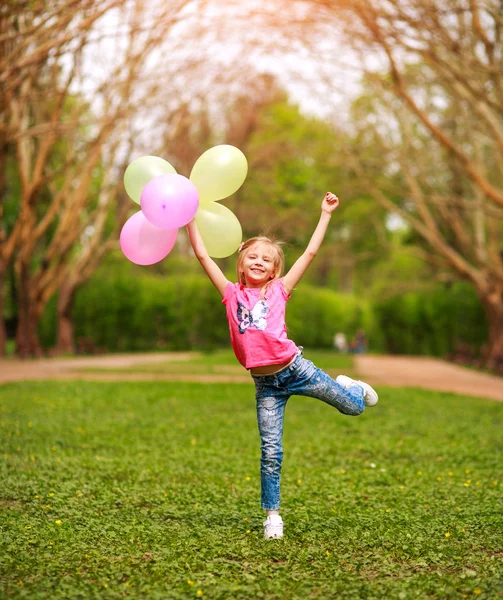 春の緑の公園で幸せから飛び降りる楽しい女の子の子供 — ストック写真