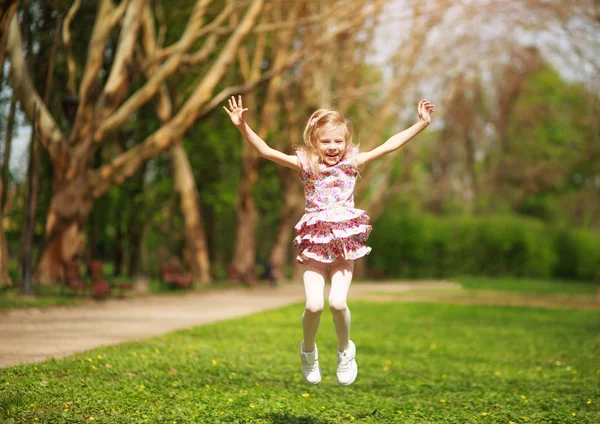 Baharın Yeşil Parkında Mutluluktan Atlayan Neşeli Küçük Kız Çocuğu — Stok fotoğraf