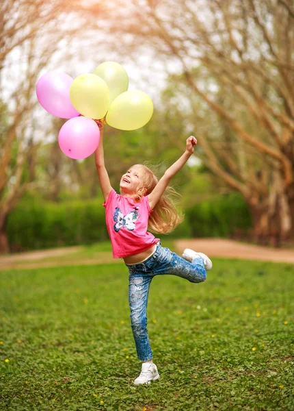 春の緑の公園で幸せから飛び降りる楽しい女の子の子供 — ストック写真