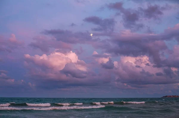 Sea coast on a background of a beautiful sky with clouds and the moon, the beautiful relaxing evening view