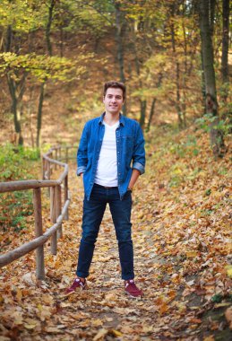 Orman parkındaki genç düşünceli ve hayalperest adam rahatlamanın ve doğanın tazeliğinin tadını çıkarıyor.