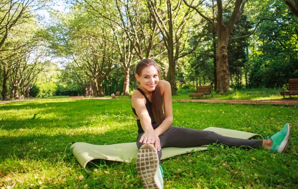 Молодая Женщина Делает Фитнес Упражнения Газоне Летнего Зеленого Парка Тренируется — стоковое фото
