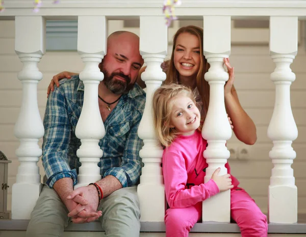 有小女儿的年轻家庭坐在家里 一起在房子的门廊上玩得很开心 — 图库照片