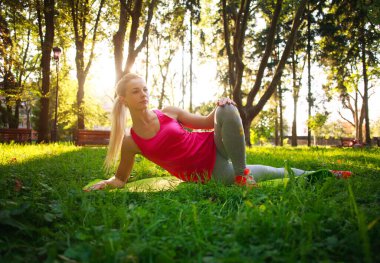 Yeşil bir parkta spor yapan genç bir atletik kız. Doğada sağlığa dikkat etmek için eğitim günü.
