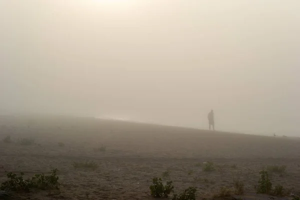 Man walking in the fog on the beach