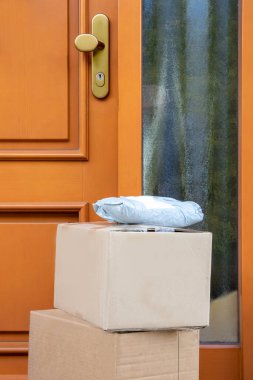 Coronavirus karantina konsepti. Salgın sırasında evin kapısına konmuş üç paketin sorumsuz teslimat servisi. Evde kal ve sosyal ilişkilerden ve mesafelerden uzak dur..