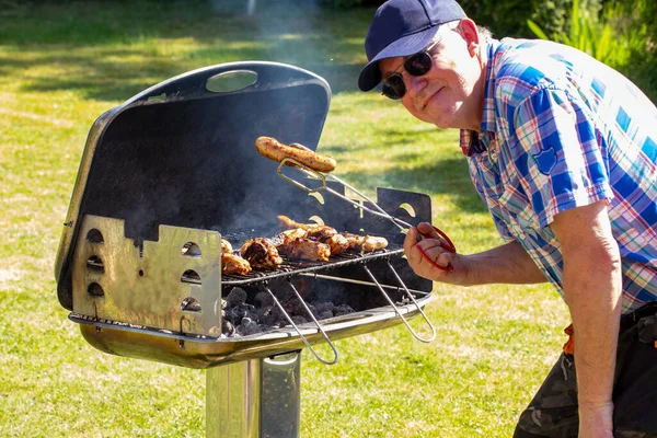 Man Charcoal Grill Holding Grilled Sausage Tongs His Hand Looking — Stock Photo, Image