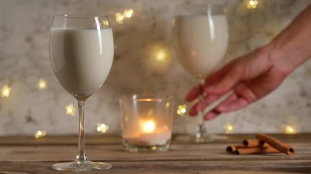 Vrouwelijke hand die het glas Eggnog pakt. Kerstborrel met advocaat. — Stockvideo