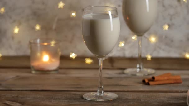 Σπιτικά παραδοσιακά χριστουγεννιάτικα ποτά eggnog στα ποτήρια με κανέλα. — Αρχείο Βίντεο
