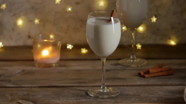 Christmas eggnog drinks with cinnamon with blinking decorative light . — Stock video