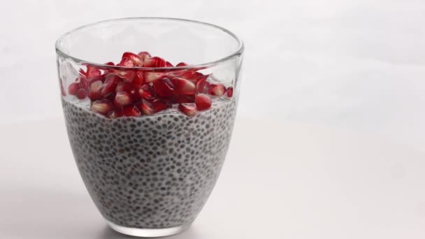 Roterande Chia pudding med granatäpple frön vit bakgrund. — Stockvideo