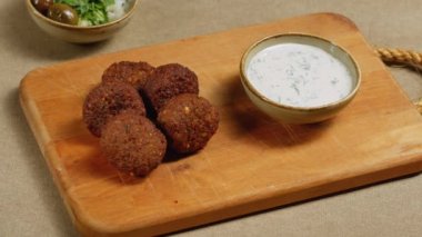 Kadınlar taze vejetaryen falafeli susam ezmesine daldırıyor, tahini..