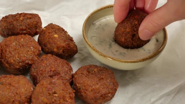 Mulheres mão mergulhando falafel vegetariano fresco em pasta de gergelim, tahini . — Vídeo de Stock