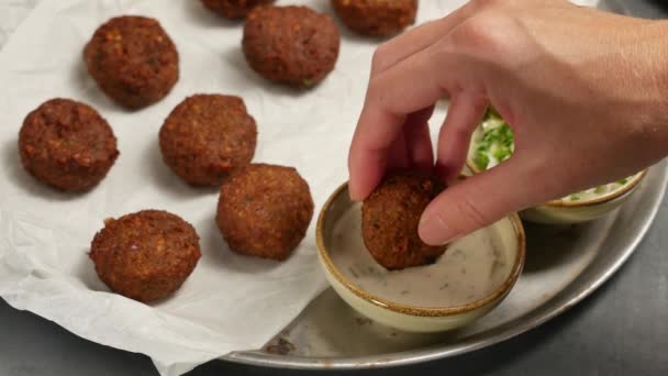 Mujeres mano sumergiendo falafel vegetariano fresco en pasta de sésamo, tahini . — Vídeos de Stock