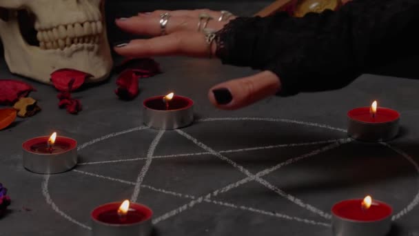 Female hand extinguishing the flame of a candles above the pentagram circle. — Stock Video