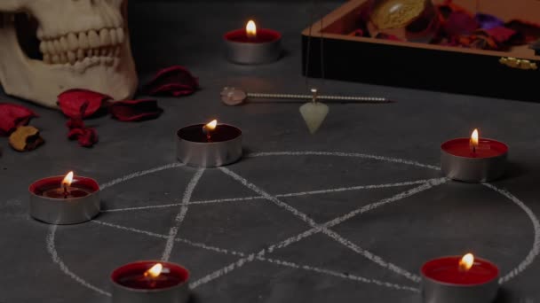 Pendulum ajaib berputar di atas pentagram pada lilin latar belakang dan tengkorak . — Stok Video