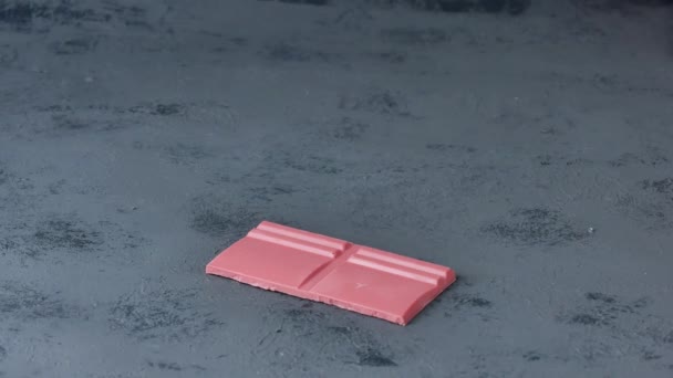 Куски сломанного рубинового шоколада, сложенные на доске . — стоковое видео