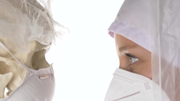 Doctor in safety coverall looking at a human skull model. — Stock Video