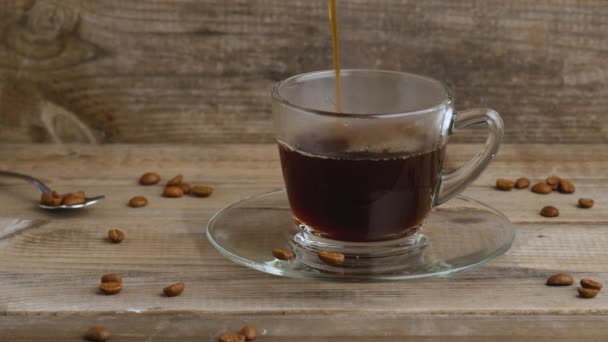 Kinemagraf. Kubek kawy i ziarna kawy. Wlewanie kawy do szklanej filiżanki. — Wideo stockowe