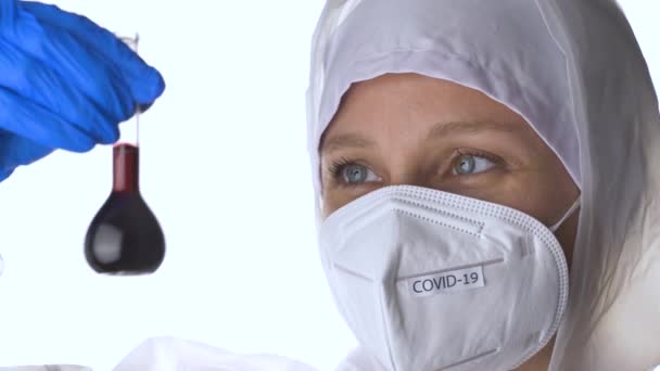 Arzt im Schutzanzug bei der Untersuchung eines Coronavirus-Reagenzglases. — Stockvideo