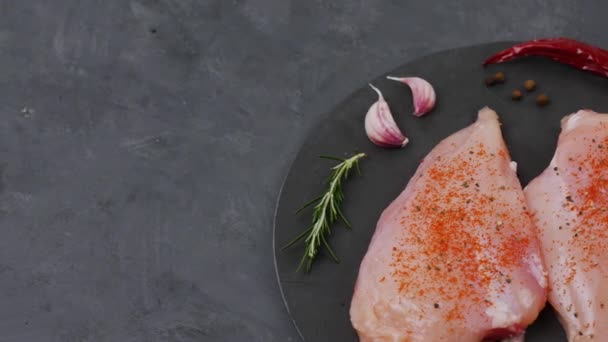 Pechuga de pollo cruda con especias y chile rota sobre un fondo gris . — Vídeo de stock