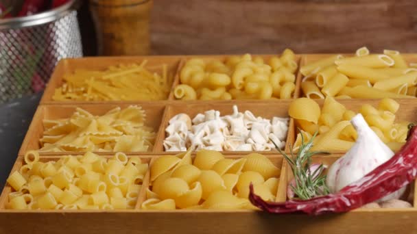 Houten doos draaiend gevuld met verschillende soorten rauwe pasta. — Stockvideo
