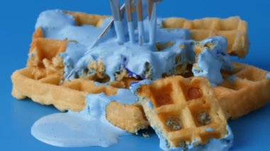 Bir Belçika waffle 'ını çatal ve bıçakla kesmeye yakın plan..