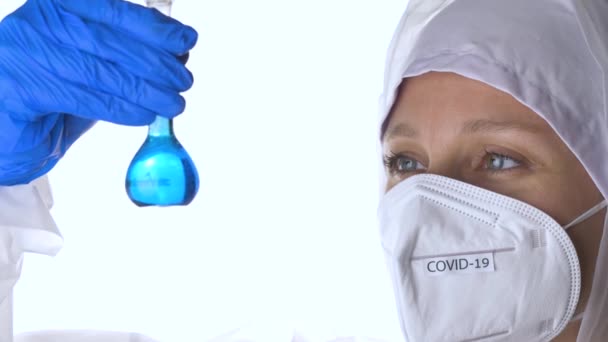 Arzt im Schutzanzug bei der Untersuchung eines Coronavirus-Reagenzglases. — Stockvideo