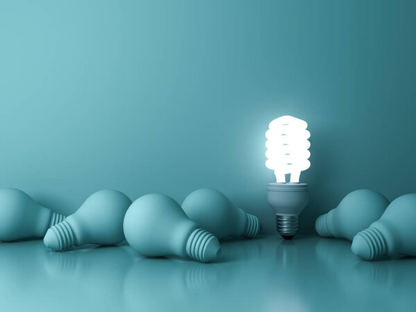 Energy saving light bulb , one glowing fluorescent lightbulb standing out from dead incandescent bulbs on green background