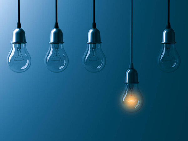 One hanging light bulb glowing different and standing out from unlit incandescent bulbs with reflection on dark cyan background , leadership and different business creative idea concept