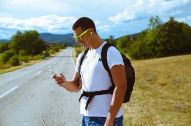 Earphon ile müzik dinlemek için akıllı telefon kullanarak adam yolculuğa,