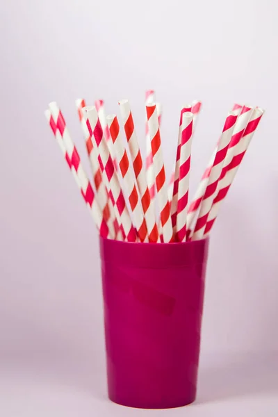 Palhas multicoloridas no copo roxo de plástico no backgr rosa — Fotografia de Stock