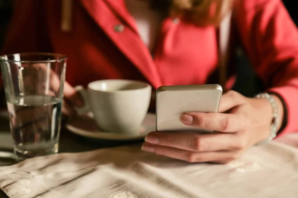 Perempuan menggunakan smartphone dan minum kopi. Tutup. — Stok Foto