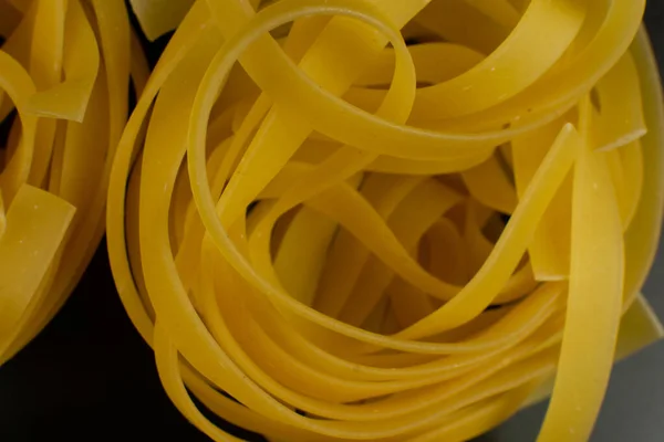 Rohe italienische Tagliatelle Pasta auf dunklem Hintergrund — Stockfoto