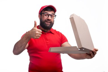 Sakallı bir adam stüdyoda beyaz bir arka planda kırmızı tişörtlü ve şapkalı bir kutu tutuyor.