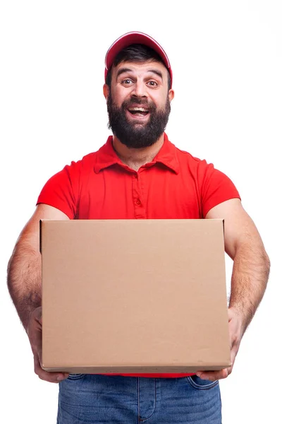 髭を生やした男が赤いTシャツに箱を持ちスタジオで白い背景に帽子をかぶって — ストック写真