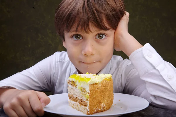 Kleiner Junge Isst Einen Kuchen Während Tisch Sitzt — Stockfoto